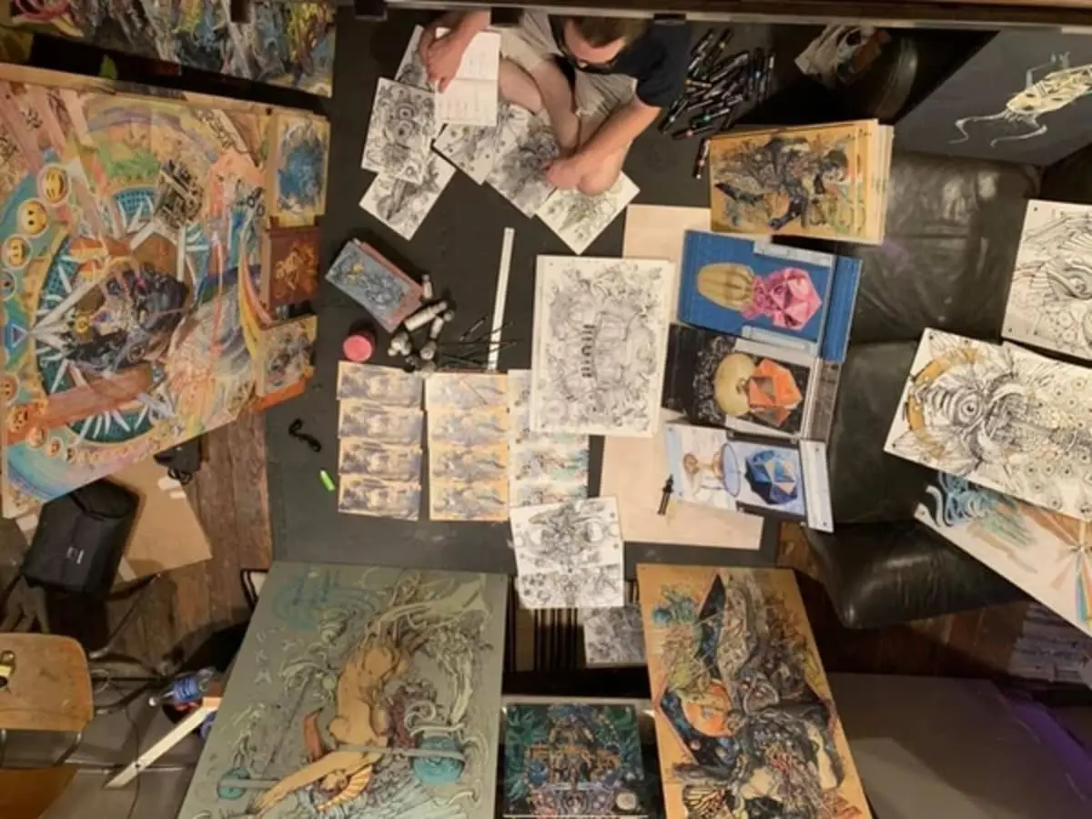 Adam One working in his studio, surrounded by paintings and drawings