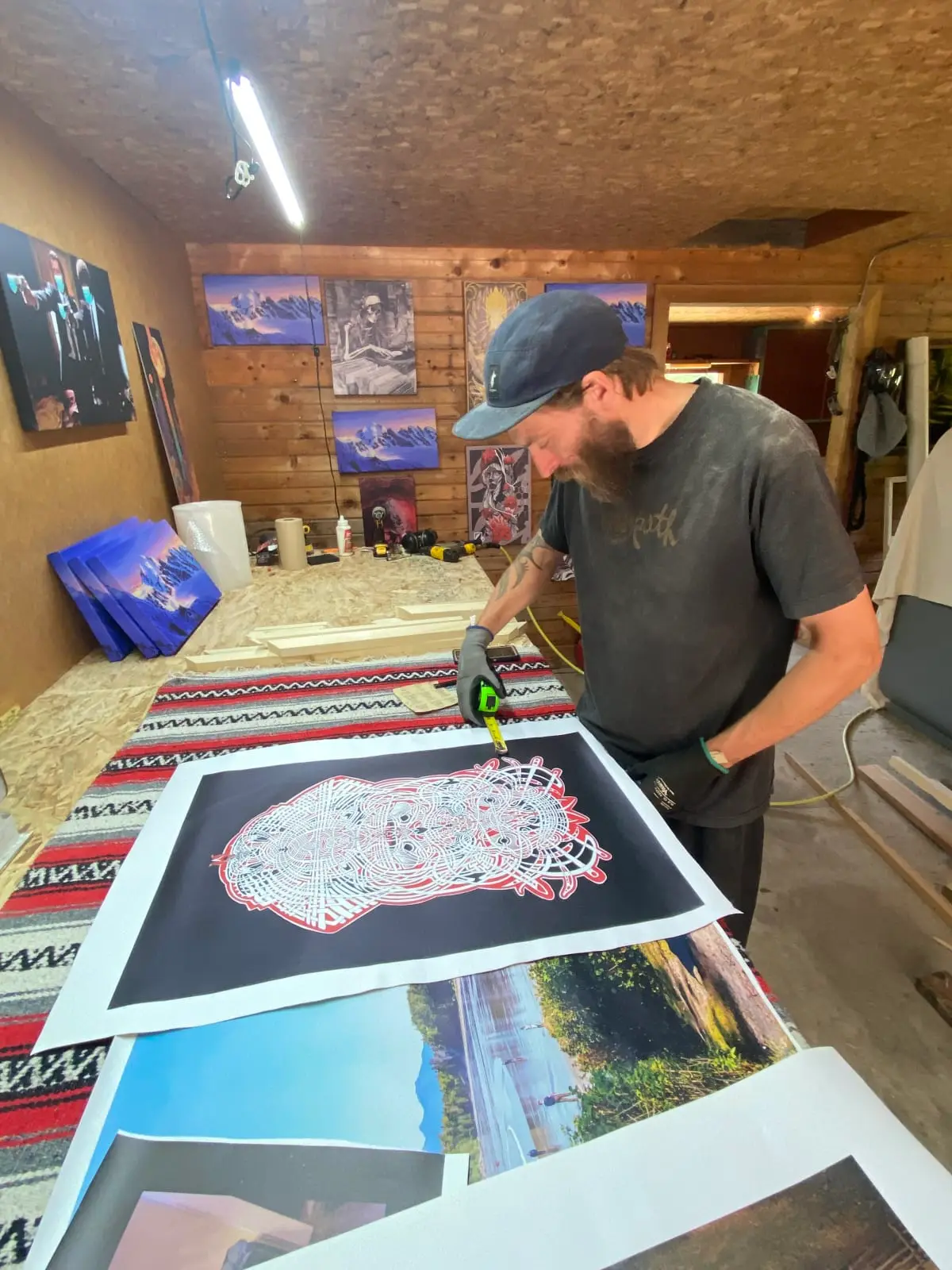 Measuring a fine-art print in the WinPrint shop, with finished canvases on the wall